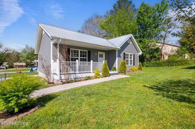ranch-style house featuring metal roof, a front lawn, and covered porch