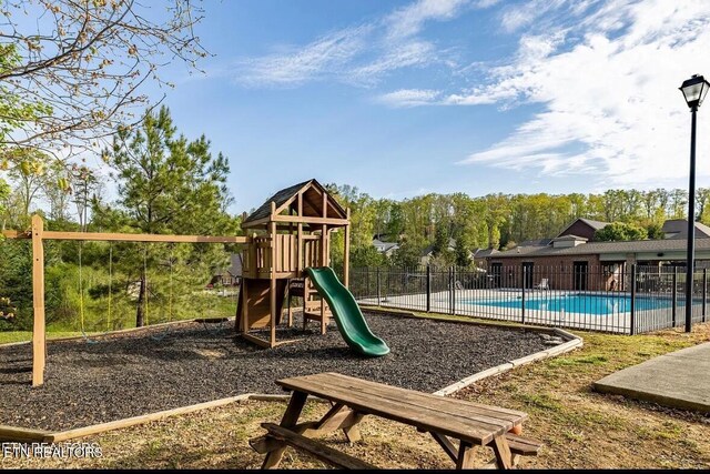 community jungle gym with a community pool and fence