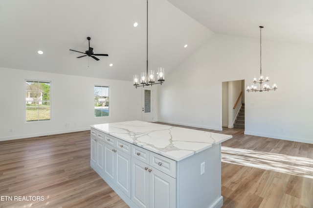 kitchen featuring open floor plan, a center island, high vaulted ceiling, pendant lighting, and ceiling fan with notable chandelier