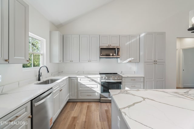 kitchen featuring a sink, light stone countertops, high vaulted ceiling, and stainless steel appliances