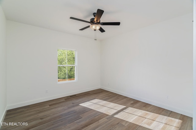 spare room with wood finished floors, baseboards, and a ceiling fan