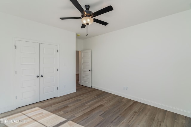 unfurnished bedroom with wood finished floors, ceiling fan, a closet, and baseboards