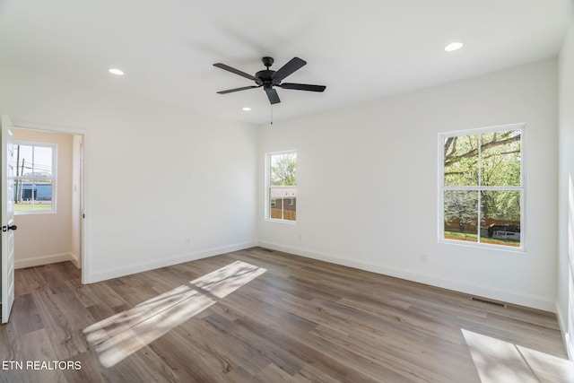 empty room with a wealth of natural light, baseboards, and wood finished floors