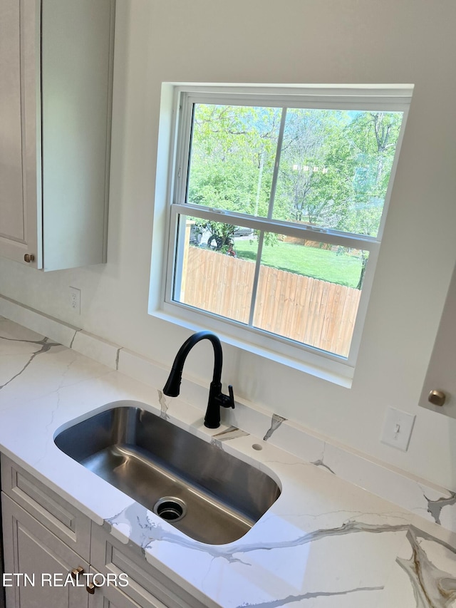 details featuring a sink and light stone countertops