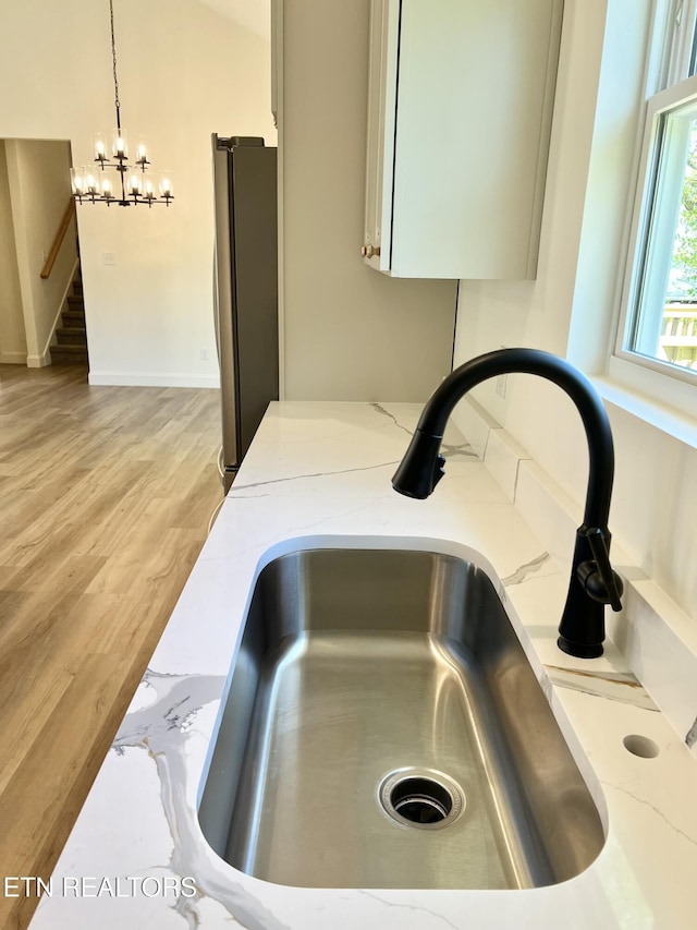 interior details featuring light wood-style flooring, freestanding refrigerator, a sink, and light stone countertops