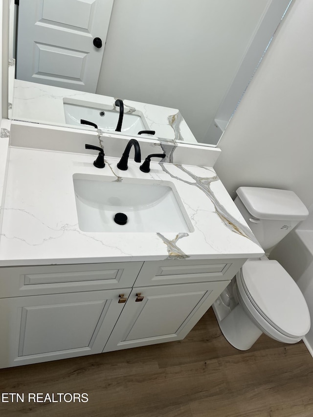 bathroom featuring toilet, wood finished floors, and vanity
