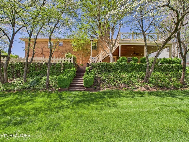 view of yard featuring stairs, fence, and ceiling fan