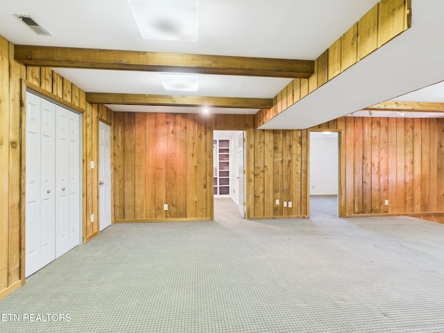 interior space featuring wooden walls, beamed ceiling, visible vents, and carpet floors