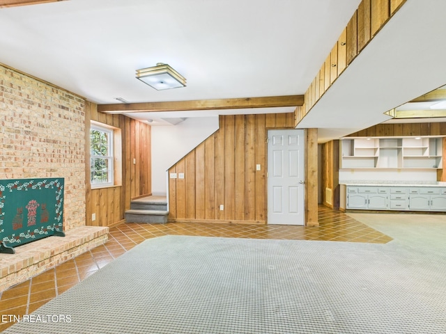 unfurnished living room with tile patterned floors, wooden walls, beam ceiling, and stairs