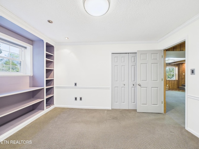 carpeted empty room featuring baseboards, a textured ceiling, and crown molding