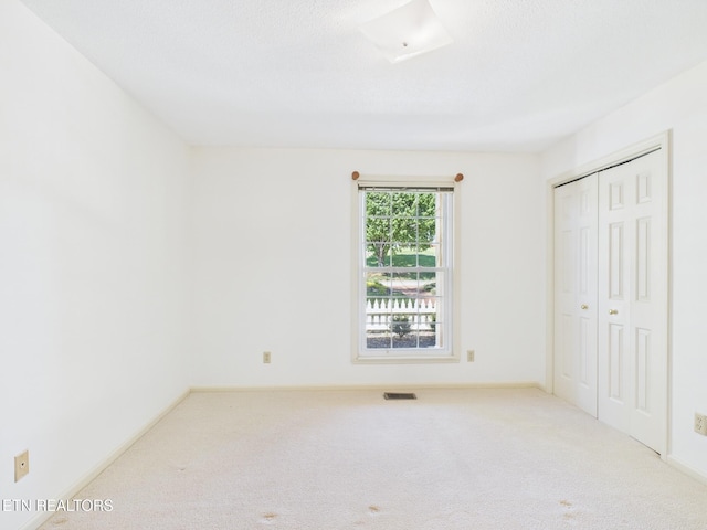 unfurnished bedroom with visible vents, baseboards, a closet, and carpet