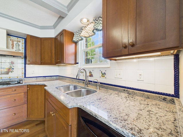 kitchen featuring crown molding, light stone counters, black stovetop, a sink, and decorative backsplash