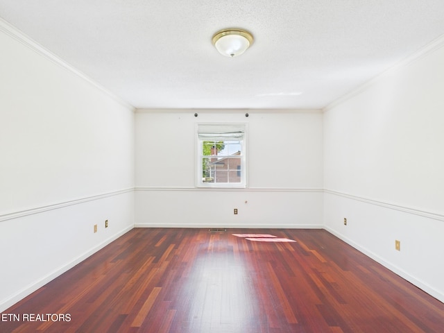 empty room featuring wood finished floors, baseboards, ornamental molding, and visible vents