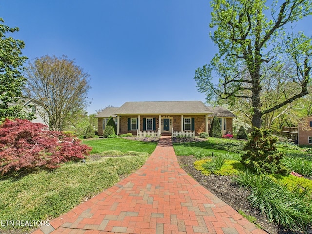 single story home with brick siding, a porch, and a front lawn
