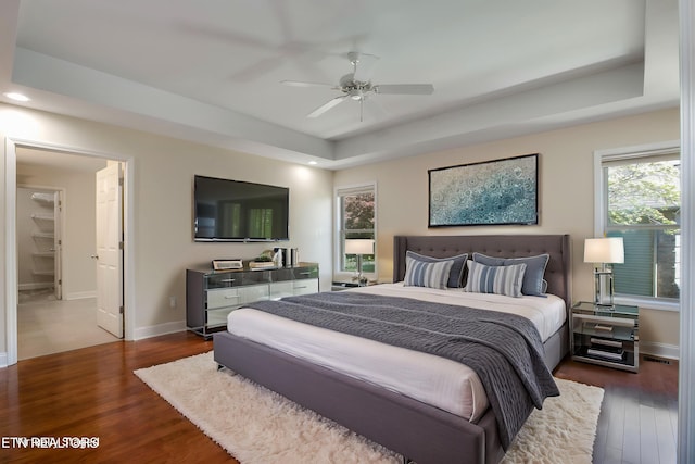 bedroom featuring recessed lighting, dark wood-style floors, a tray ceiling, baseboards, and ceiling fan
