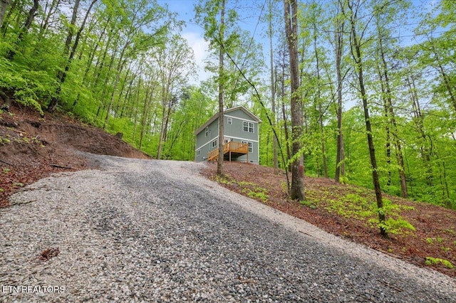 view of road featuring gravel driveway and a view of trees