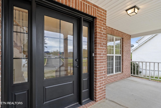property entrance featuring brick siding and covered porch