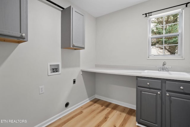 laundry room featuring hookup for a washing machine, light wood-style flooring, hookup for an electric dryer, a sink, and cabinet space