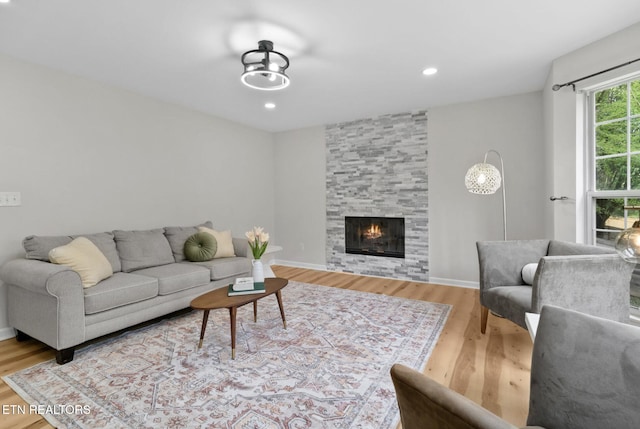 living area featuring recessed lighting, a fireplace, baseboards, and wood finished floors