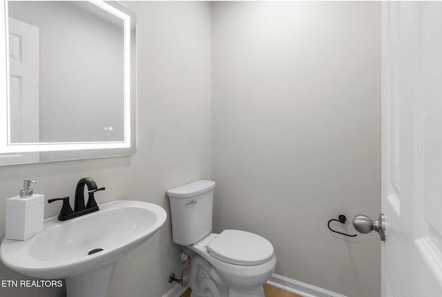 half bathroom featuring a sink, toilet, and baseboards