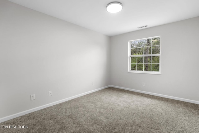 carpeted spare room with visible vents and baseboards