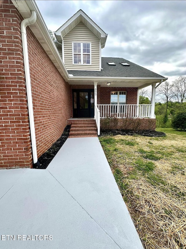 property entrance with brick siding and covered porch