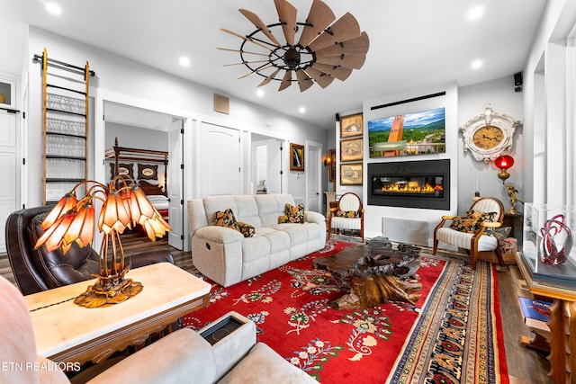 living area featuring a glass covered fireplace, wood finished floors, recessed lighting, and a ceiling fan