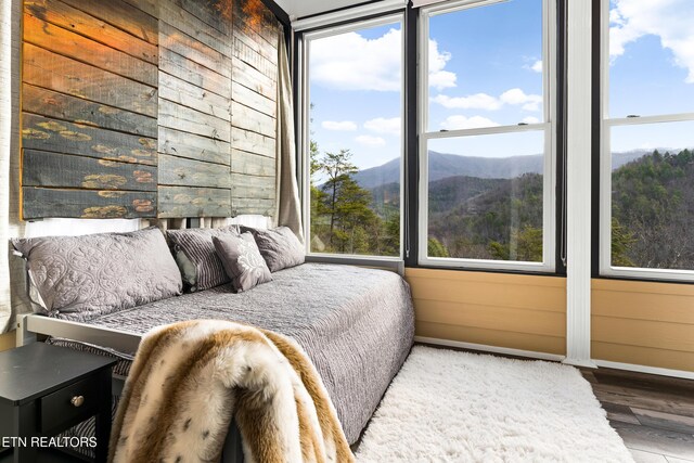 bedroom featuring wood finished floors, baseboards, a mountain view, and wooden walls