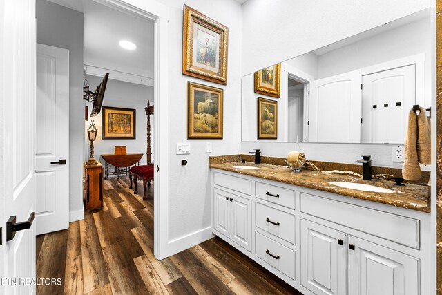 full bath featuring wood finished floors, baseboards, and double vanity
