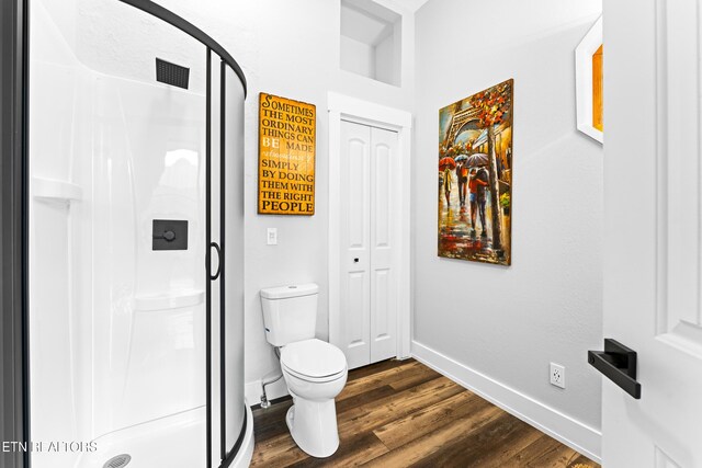 bathroom featuring a stall shower, baseboards, and wood finished floors