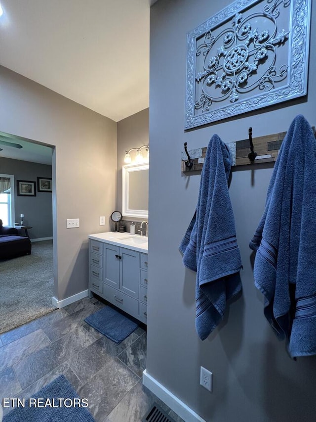 bathroom with baseboards, stone finish floor, and vanity