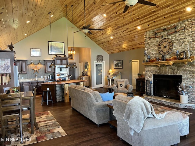 living area with a stone fireplace, high vaulted ceiling, dark wood-style floors, and ceiling fan with notable chandelier