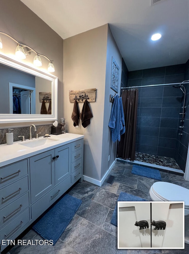bathroom featuring vanity, baseboards, stone tile flooring, and a stall shower