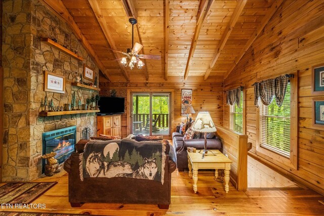 living room with lofted ceiling with beams, a stone fireplace, hardwood / wood-style flooring, and wood ceiling