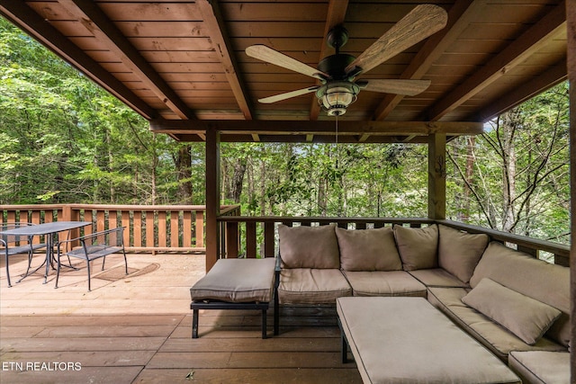 wooden deck featuring a wooded view, a ceiling fan, and an outdoor hangout area