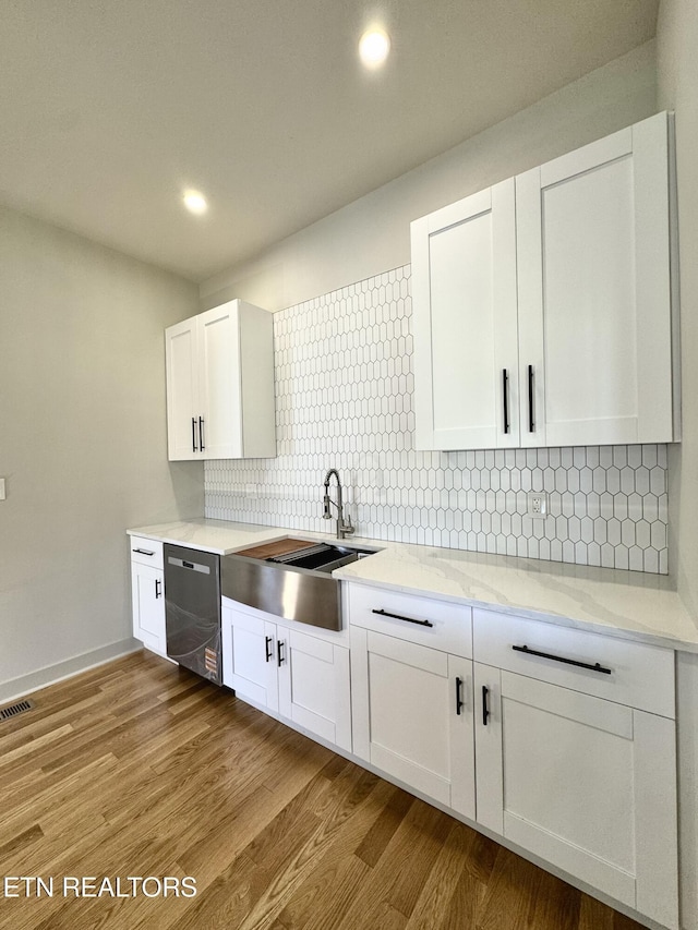 304 Broad St, Sweetwater, TN 37874 - kitchen with wood finished floors, stainless steel dishwasher, a sink, and white cabinetry