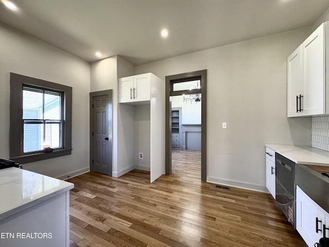 304 Broad St, Sweetwater, TN 37874 - kitchen featuring stainless steel dishwasher, white cabinets, light stone counters, wood finished floors, and baseboards