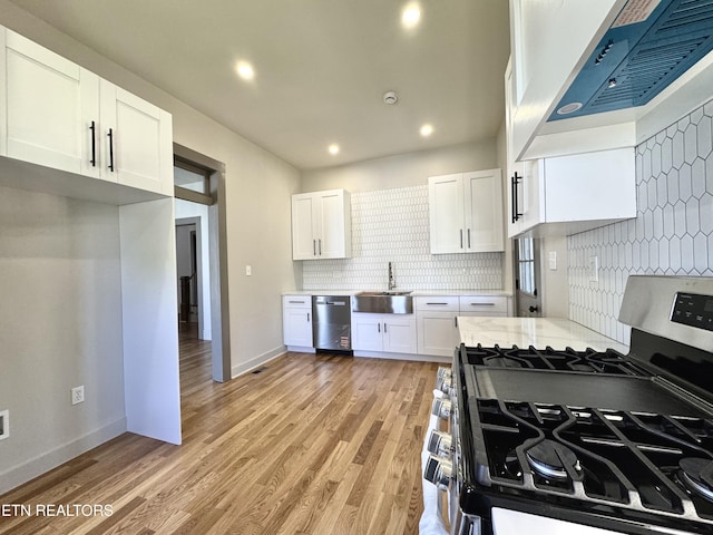 304 Broad St, Sweetwater, TN 37874 - kitchen with wall chimney range hood, white cabinetry, decorative backsplash, stainless steel appliances, and a sink