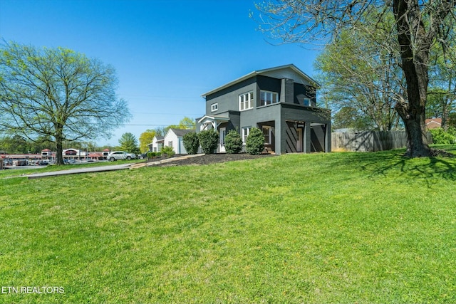 view of front facade featuring driveway, fence, and a front lawn