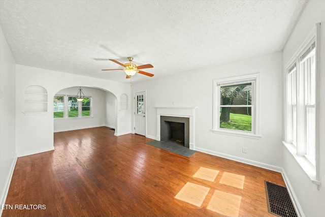 unfurnished living room featuring a textured ceiling, wood finished floors, a ceiling fan, and visible vents