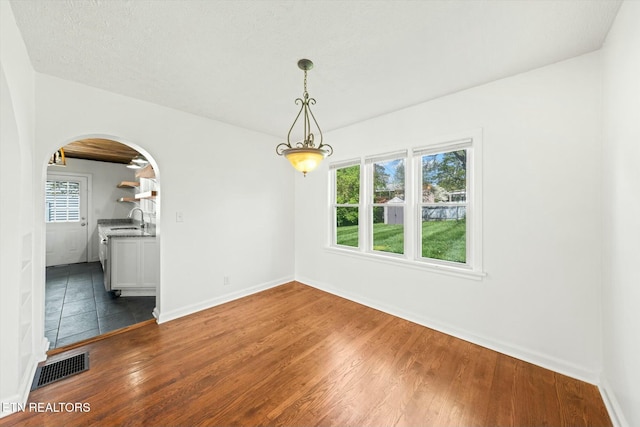 unfurnished dining area featuring a sink, dark wood finished floors, visible vents, and plenty of natural light