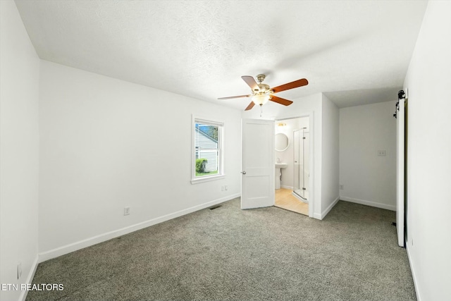 unfurnished bedroom with ensuite bathroom, baseboards, visible vents, a textured ceiling, and carpet floors