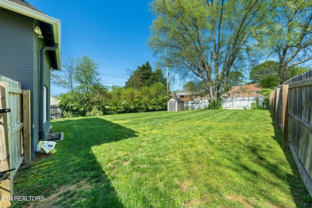 view of yard with a shed, a fenced backyard, and an outbuilding