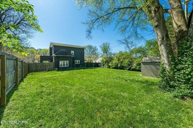 view of yard with a fenced backyard, a storage shed, and an outbuilding