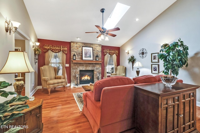 10 Claremont Cir, Fairfield Glade, TN 38558 - living area with a fireplace, vaulted ceiling with skylight, a healthy amount of sunlight, and light wood-style flooring