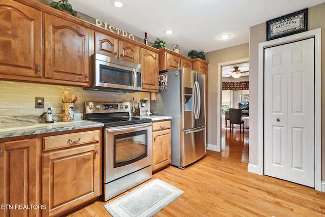 10 Claremont Cir, Fairfield Glade, TN 38558 - kitchen with brown cabinets, appliances with stainless steel finishes, tasteful backsplash, and light wood-style flooring