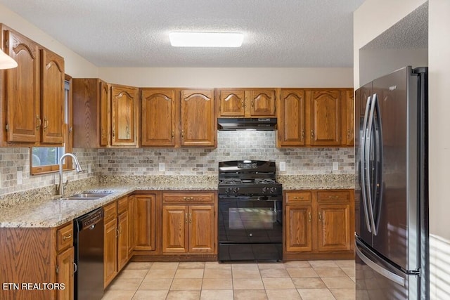 kitchen featuring brown cabinetry, a sink, black appliances, and exhaust hood