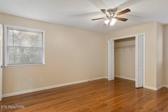 unfurnished bedroom with a closet, baseboards, a textured ceiling, ceiling fan, and wood finished floors