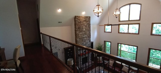 hallway featuring a chandelier, wood finished floors, a towering ceiling, and visible vents