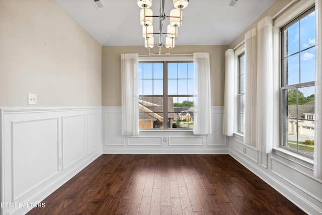 unfurnished dining area featuring dark wood-style flooring, a notable chandelier, a healthy amount of sunlight, and vaulted ceiling